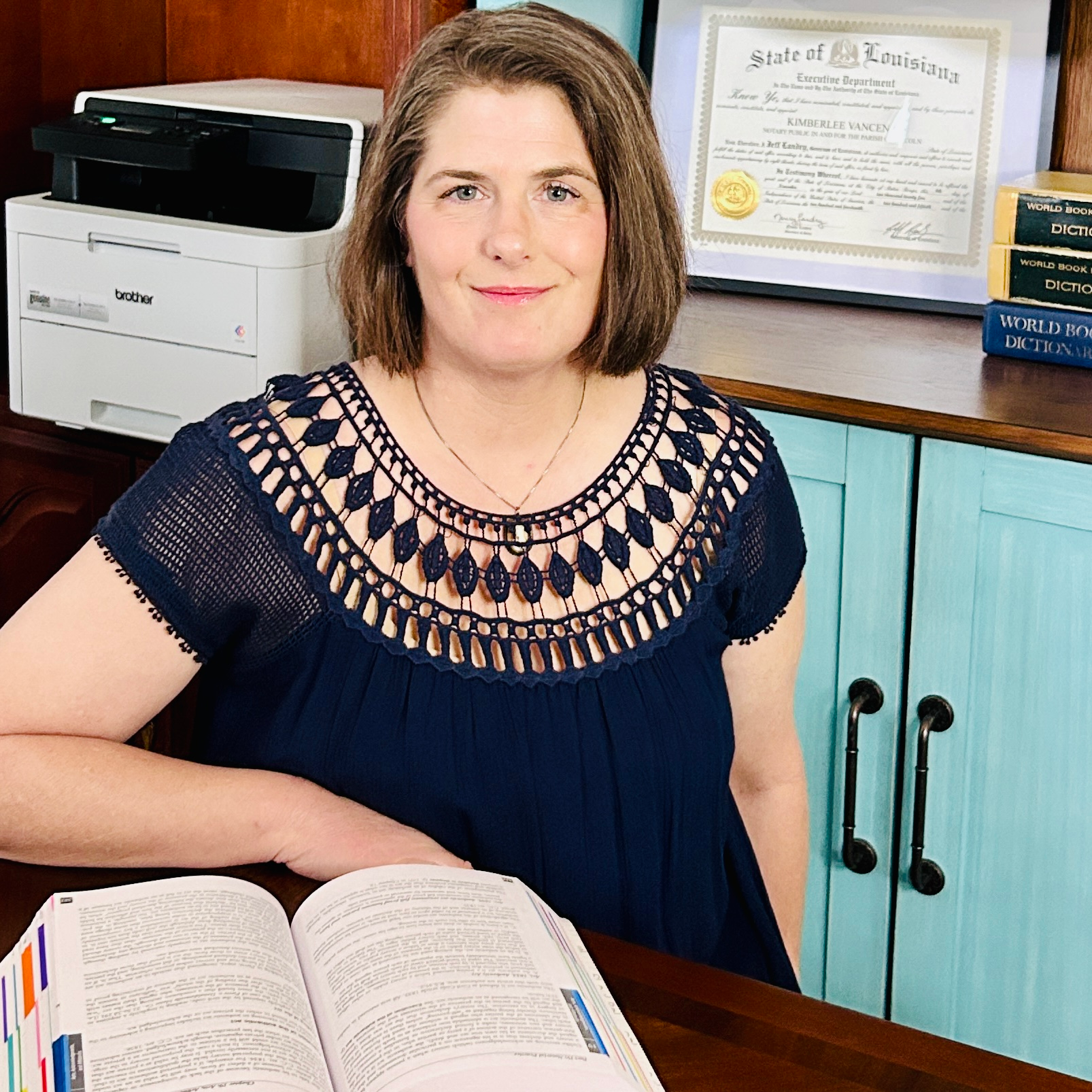 Kim Vancena, Ruston Louisiana notary, seated at desk with Louisiana Civil Code open, looking at camera